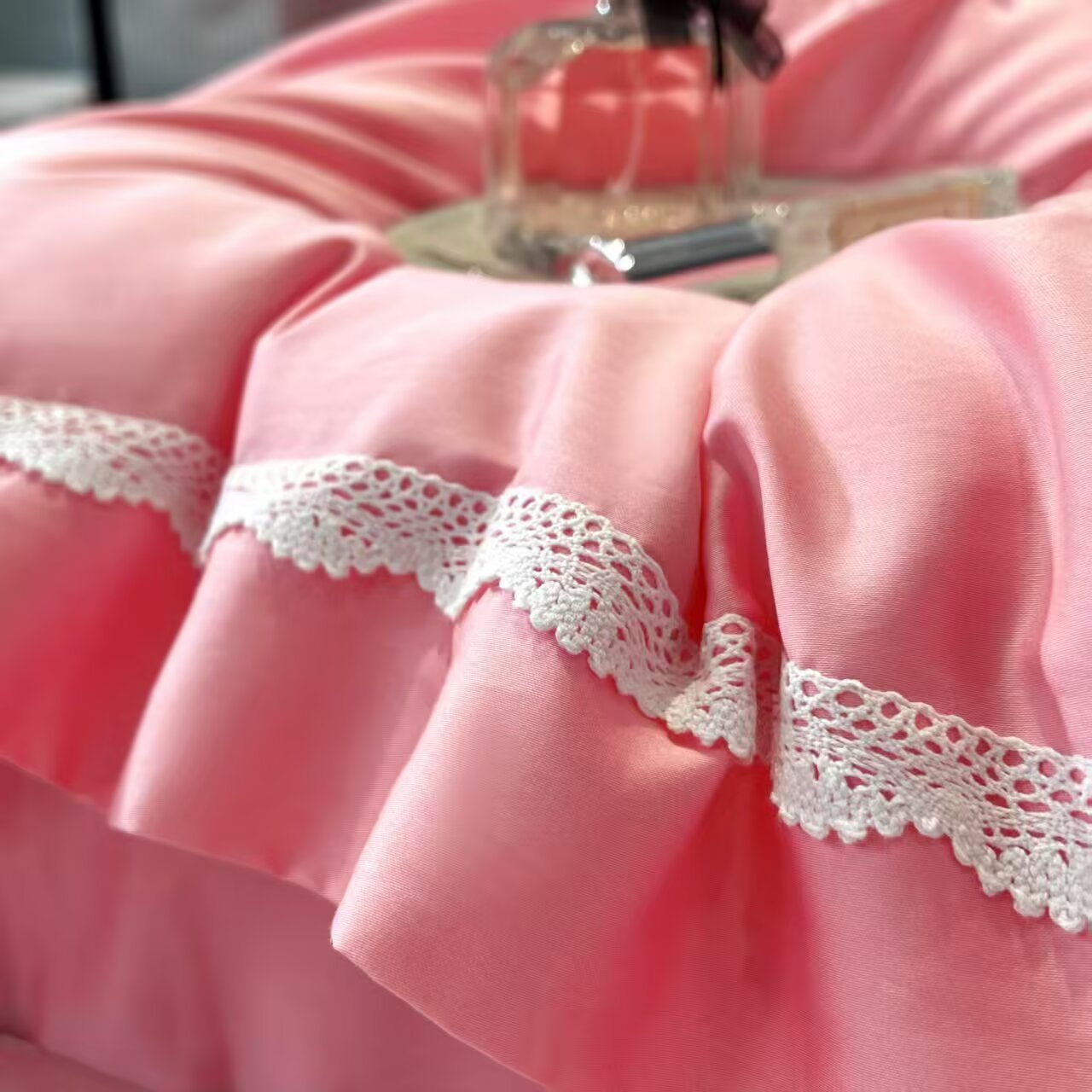 White lace border detail on pink satin bedding